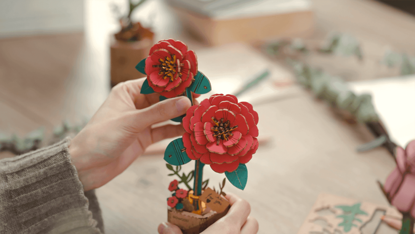 Close-up of hands holding the Rowood Red Camellia TW031 wooden flower after assembly