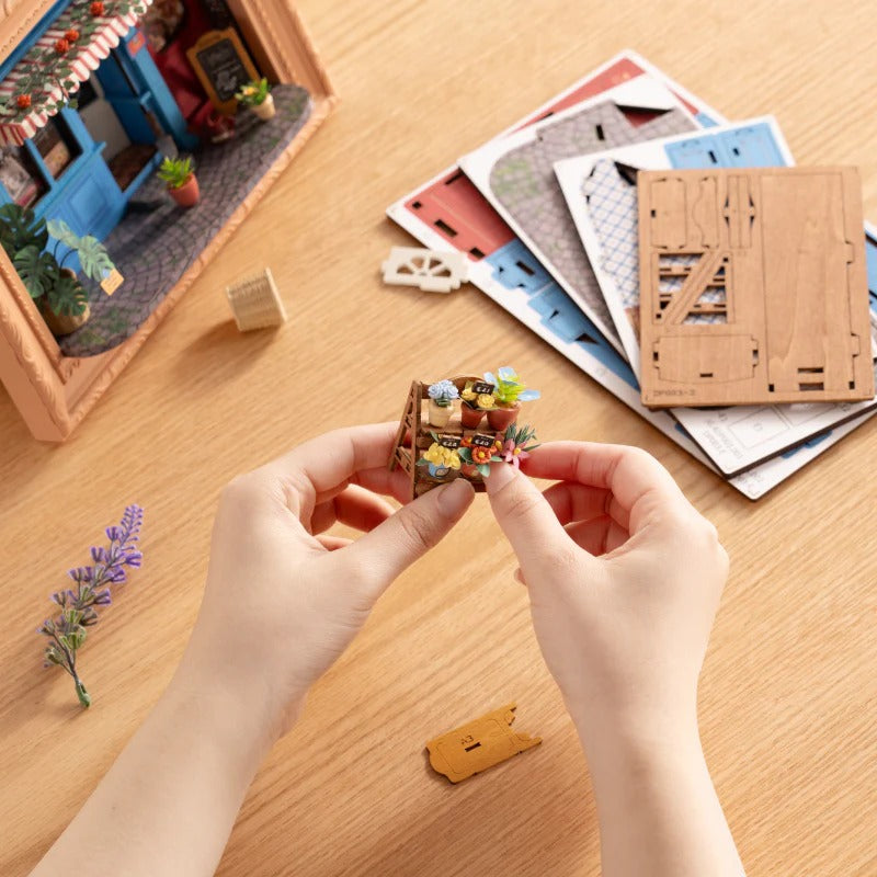 Rolife Daily Fresh Flower DP003 DIY assembly close-up showing hands building the miniature flower shelf with laser-cut parts