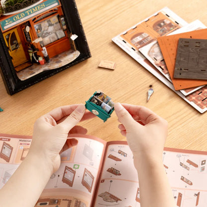 Rolife Old Times Bookstore DP004 DIY assembly process showing hands building the miniature book display