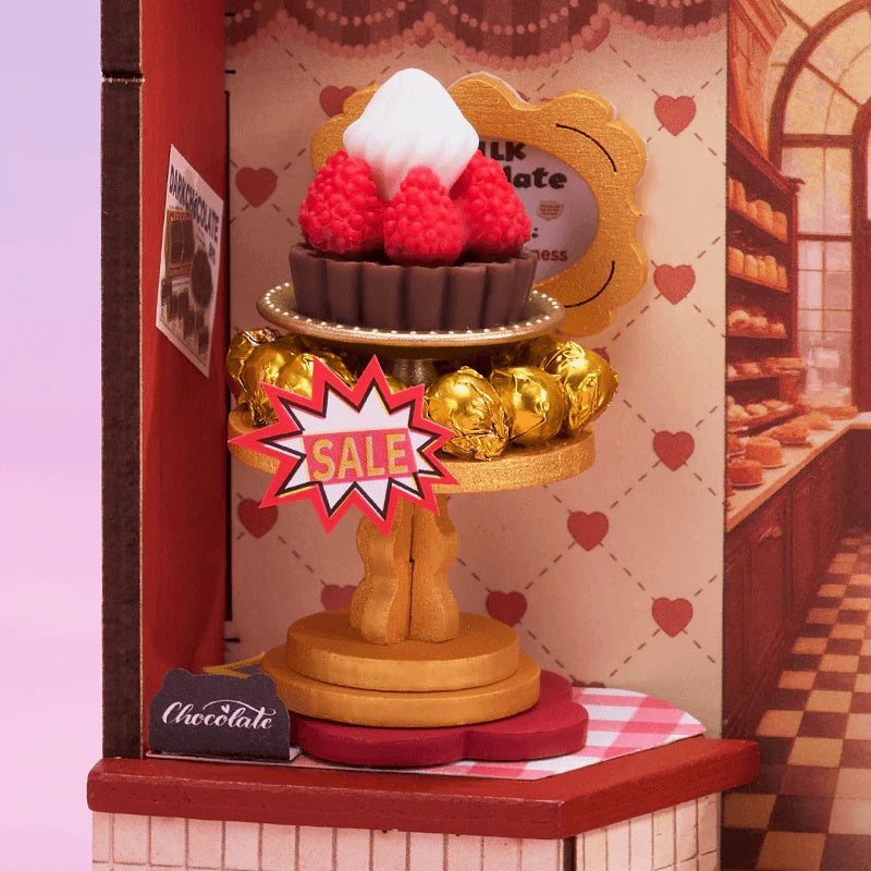 Rolife Sweet Chocolate Shop DS046 close-up of sale dessert display with raspberry cake and gold chocolates
