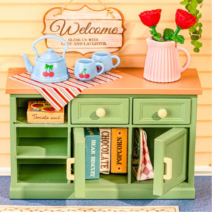 Close-up of the Sunshine Sip Porch DWS07B green cabinet, cherry tea set, flowers and storage details.